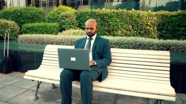 Ofis yakınında mavi takım elbise giyen dizüstü bilgisayar tutan Hintli işadamı