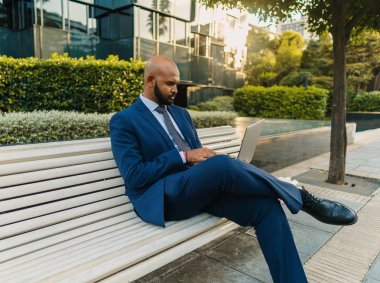 Ofis yakınında mavi takım elbise giyen dizüstü bilgisayar tutan Hintli işadamı