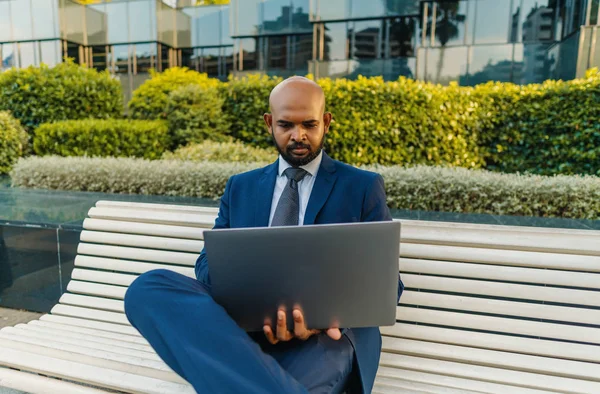 Hombre de negocios indio sosteniendo portátil portátil con traje azul cerca de la oficina —  Fotos de Stock