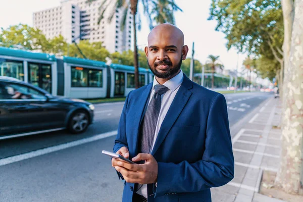 Indian businessman wearing blue suit standing near office or hotel.