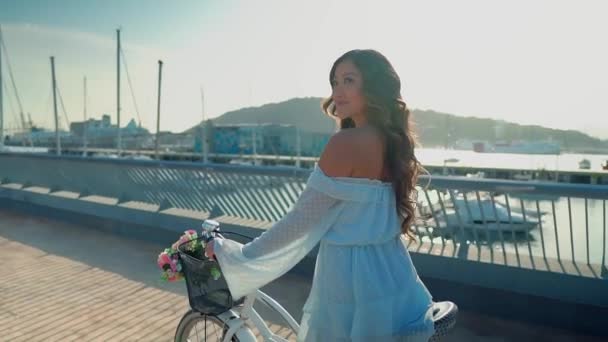 Modèle asiatique en robe bleue monte un vélo blanc sur la terrasse de la mer — Video