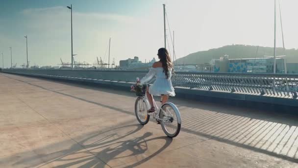 Asiatisk modell i en blå klänning rider en vit cykel på havet terrass — Stockvideo