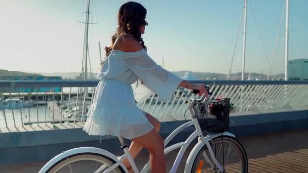 Aziatische model in een blauwe jurk rijdt op een witte fiets op zee terras — Stockvideo