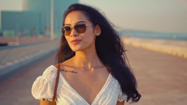 Vacker flicka i den vita klänningen promenader längs strandpromenaden — Stockvideo