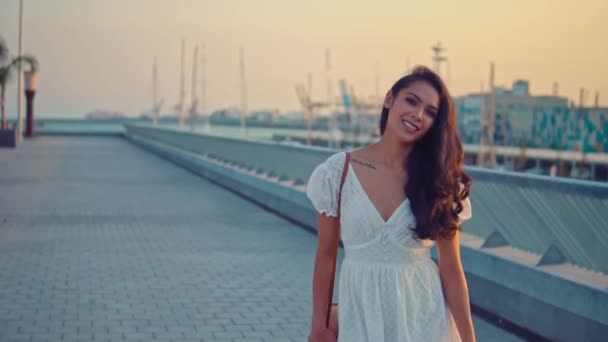 Όμορφο κορίτσι με το λευκό φόρεμα που περπατάει κατά μήκος του θαλάσσιου περιπάτου — Αρχείο Βίντεο