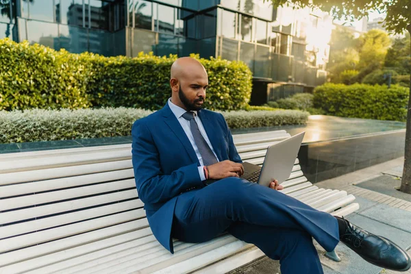 Hombre de negocios indio sosteniendo portátil portátil con traje azul cerca de la oficina —  Fotos de Stock