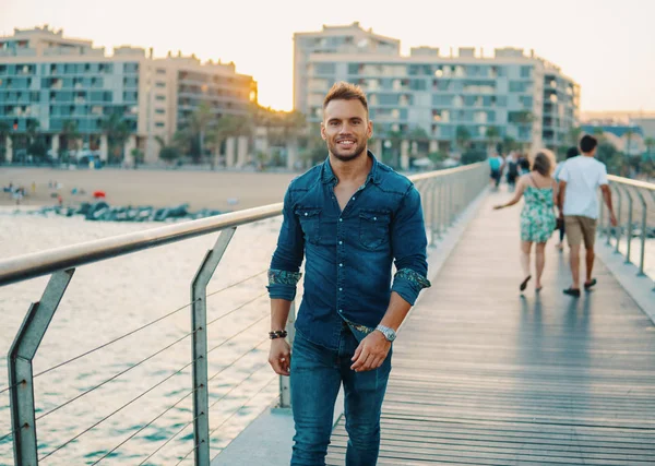 Un joven guapo en el puente cerca de la hermosa playa . —  Fotos de Stock