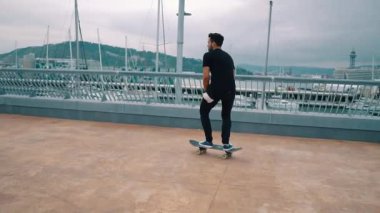 Kaykaycı modern şehir terasında bir kaykay sürmek.