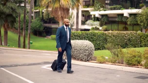 Homem de negócios indiano vestindo terno azul andando com saco de viagem ou mala — Vídeo de Stock