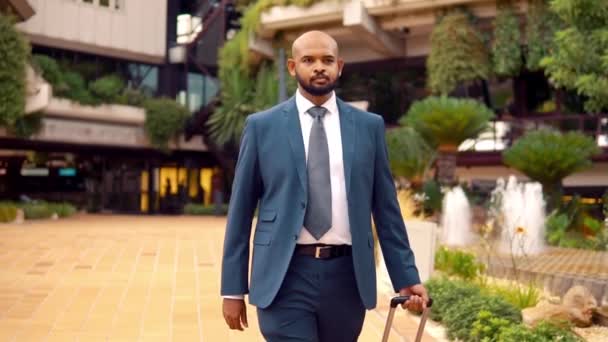 Homem de negócios indiano vestindo terno azul andando com saco de viagem ou mala — Vídeo de Stock