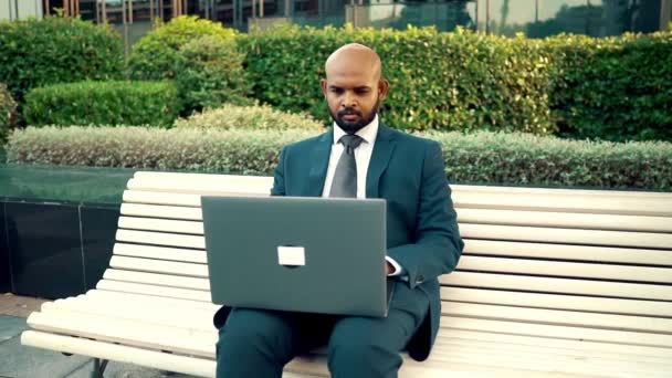 Ofis yakınında mavi takım elbise giyen dizüstü bilgisayar tutan Hintli işadamı — Stok video