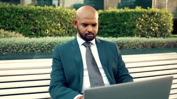 オフィスの近くに青いスーツを着てノートパソコンを持つインドのビジネスマン — ストック動画