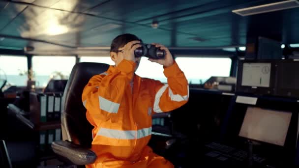 Oficial de cubierta filipino en el puente del buque o barco mirando a través de binoculares — Vídeo de stock