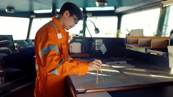 Filipino deck Officer on bridge of vessel or ship. He is plotting position on chart — Stock Video
