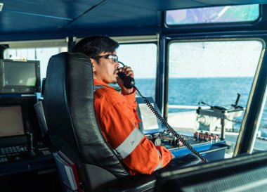 Filipinli güverte subayı gemi ya da gemi köprüsünde. GMDSS VHF radyosunda konuşuyor.