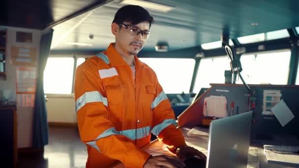 Филиппинский офицер на палубе на мостике судна или корабля. Он использует ноутбук, электронные документы в море — стоковое видео