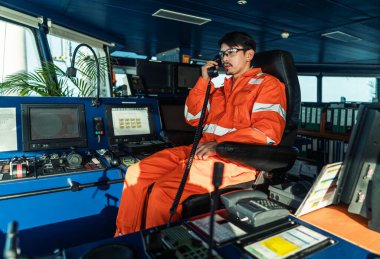 Filipinli güverte subayı gemi ya da gemi köprüsünde. GMDSS VHF radyosunda konuşuyor.