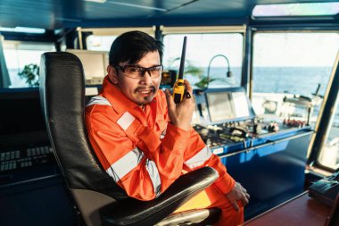 Filipinli güverte subayı gemi ya da gemi köprüsünde. GMDSS VHF radyosunda konuşuyor.