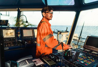 Filipino deck Officer on bridge of vessel or ship. He is speaking on GMDSS VHF radio clipart