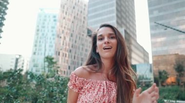 Modern şehirde arka planda gökdelenlerle poz veren seksi şık elbiseli bir kadın.