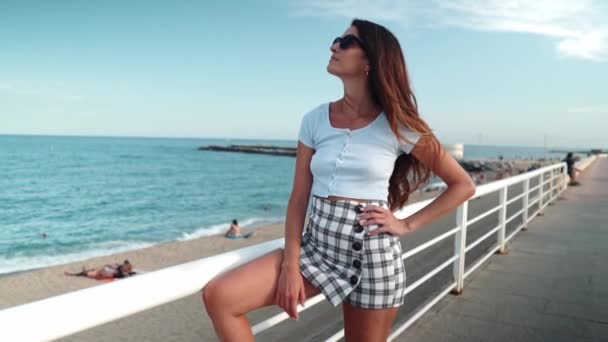 Женщина в сексуальной стильной одежде позирует в современном городе с небоскребами на заднем плане — стоковое видео