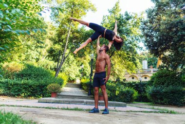 Güzel erkek ve kadın bahçede ya da parkta akroyoga yapıyor.