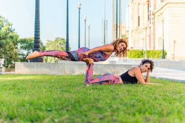 Bahçede veya parkta akroyoga yapan iki güzel kadın.