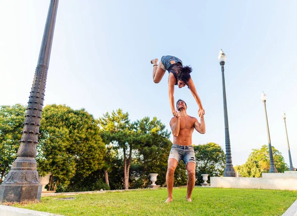 Hermoso hombre y mujer haciendo acroyoga en el césped del parque de la ciudad —  Fotos de Stock