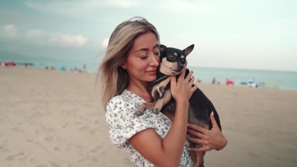 Liten hund som heter Artur med ägare, ung kvinna, spelar på stranden — Stockvideo