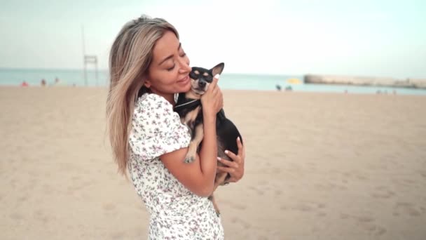 Liten hund som heter Artur med ägare, ung kvinna, spelar på stranden — Stockvideo