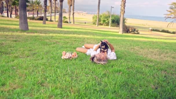 Pequeno cão chamado Artur com proprietário relaxante na grama — Vídeo de Stock