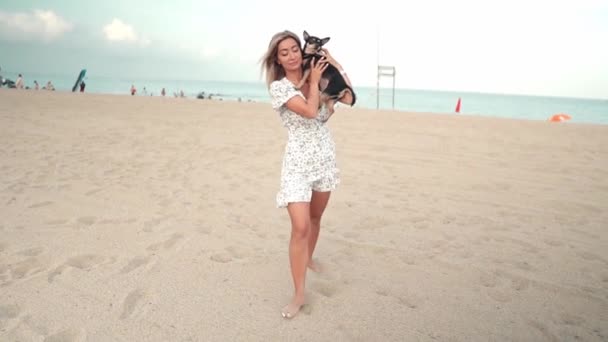 所有者とアーサーという名前の小さな犬,若い女性,ビーチで遊んで — ストック動画
