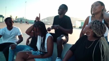 Bir grup modern Afrikalı siyahi arkadaş birlikte mutlu mesut oturuyorlar.