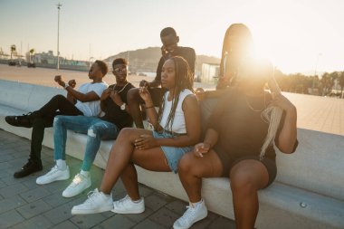 Bir grup modern Afrikalı siyahi arkadaş birlikte mutlu mesut oturuyorlar.