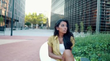 Güzel atletik kız modern şehirde uzun tahtasıyla oturuyor.