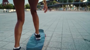 Güzel atletik kız modern şehirde uzun bir sörf tahtası kullanıyor.