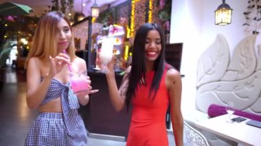 İki çekici genç bayan arkadaş birlikte kokteyl içiyorlar.