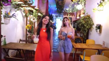 İki çekici genç bayan arkadaş birlikte kokteyl içiyorlar.