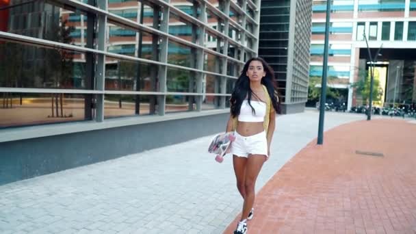 Pretty athletic girl rides a longboard in modern city — Stock Video