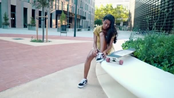 Όμορφη αθλητική κοπέλα κάθεται με ένα longboard στη σύγχρονη πόλη — Αρχείο Βίντεο