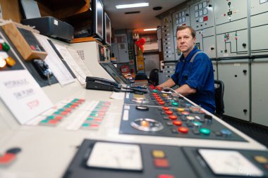 Marine engineer officer controlling vessel engines and propulsion in engine control room clipart