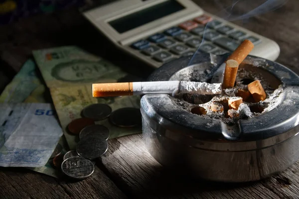 cigarette and calculator with money. in Concept how many cost you pay to buy cigarette in year Month and day