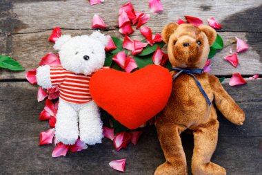 İki oyuncak ayı oyuncak bebek var aşık gül yaprakları arka plan ile Sevgililer günü içinde olmak..