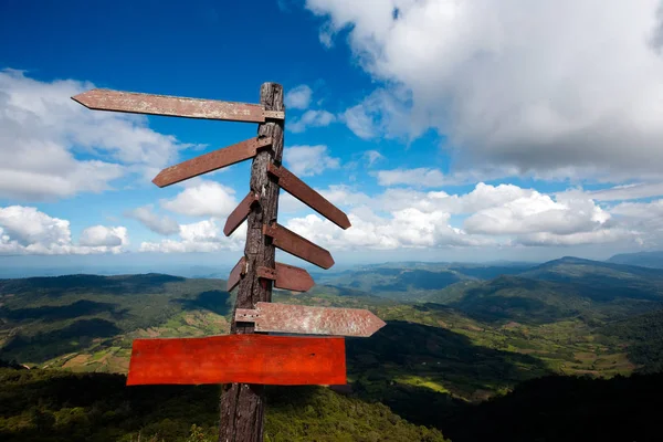 Empty plank and wood guide post on the blue sky with Mountain ba