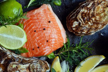  Flatlay. Karanlık bir arka plan üzerinde taze deniz ürünlerinin bileşimi. Alabalık ve istiridye otlar ve limon ile.