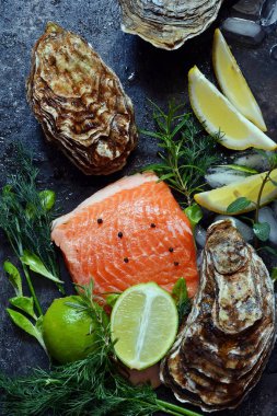  Flatlay. Karanlık bir arka plan üzerinde taze deniz ürünlerinin bileşimi. Alabalık ve istiridye otlar ve limon ile.