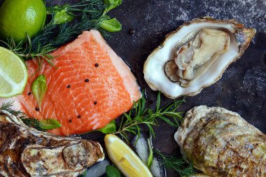  Flatlay. Karanlık bir arka plan üzerinde taze deniz ürünlerinin bileşimi. Alabalık ve istiridye otlar ve limon ile.