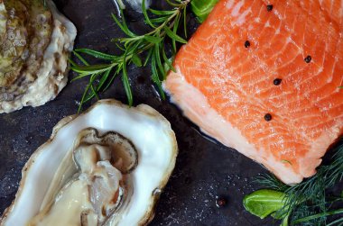 Flatlay. Karanlık bir arka plan üzerinde taze deniz ürünlerinin bileşimi. Alabalık ve istiridye otlar ve limon ile.