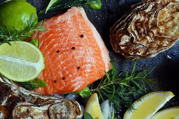  Flatlay. Karanlık bir arka plan üzerinde taze deniz ürünlerinin bileşimi. Alabalık ve istiridye otlar ve limon ile.