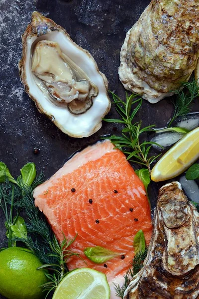  Flatlay. Karanlık bir arka plan üzerinde taze deniz ürünlerinin bileşimi. Alabalık ve istiridye otlar ve limon ile.